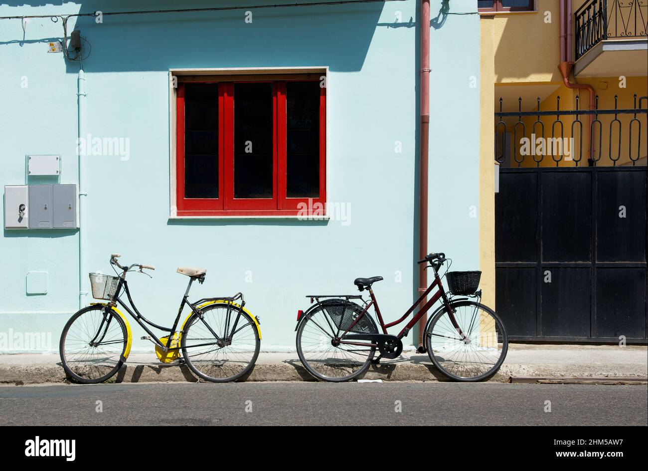 Active life style concept - two bicycles near house in sunny summer day. No people, horizontal photo. Two bicycles in the street, transport. Yellow an Stock Photo