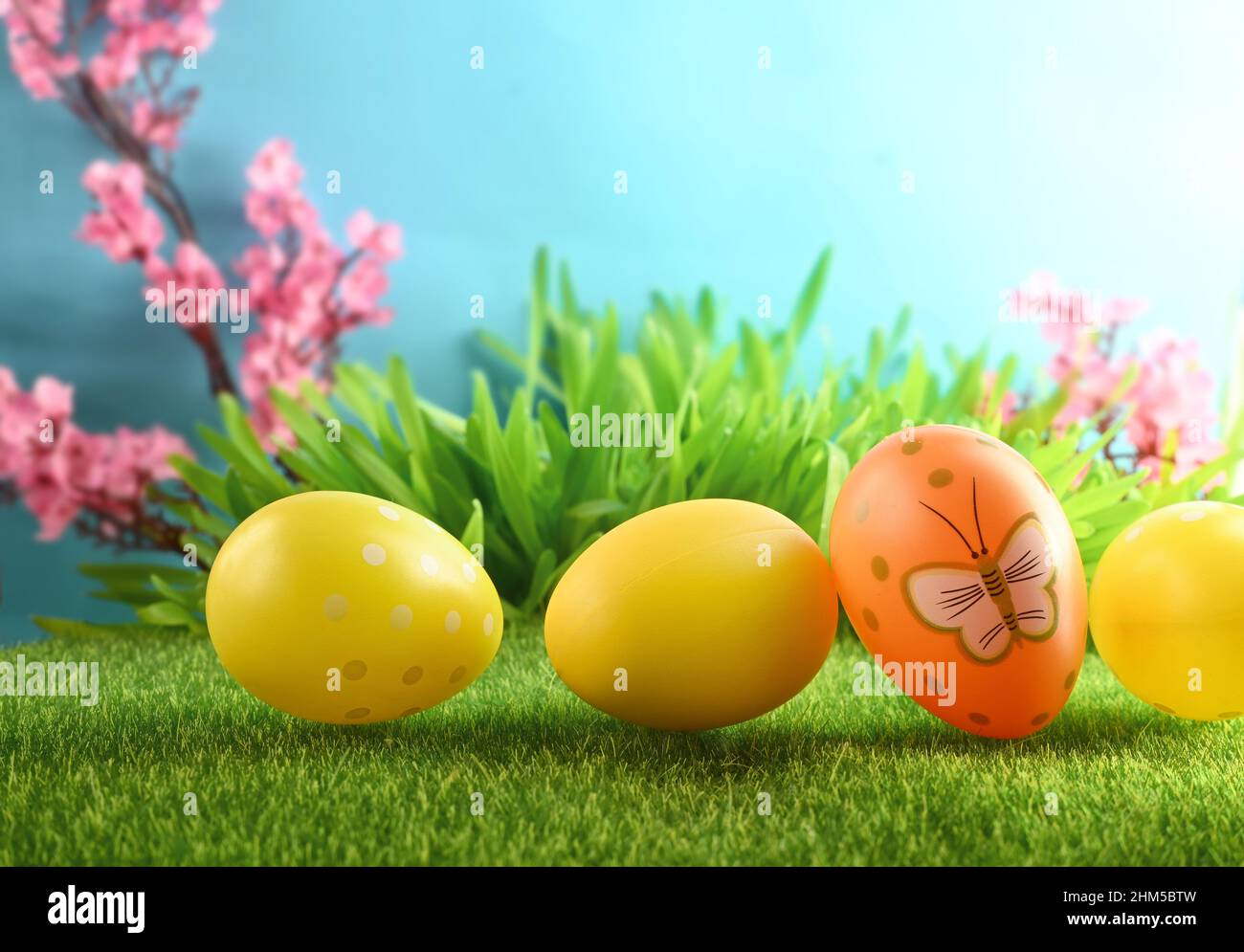 Easter eggs on green grass on blue background. Easter card. Stock Photo