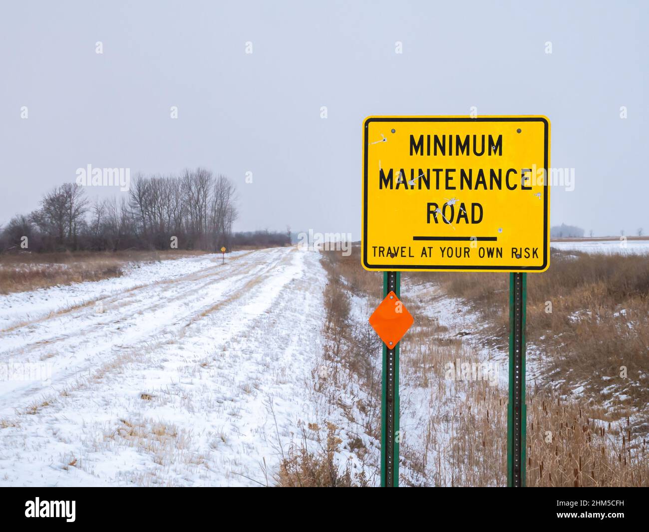 Yellow Road Sign warning of MINIMUM MAINTENANCE ROAD In rural Minnesota Stock Photo