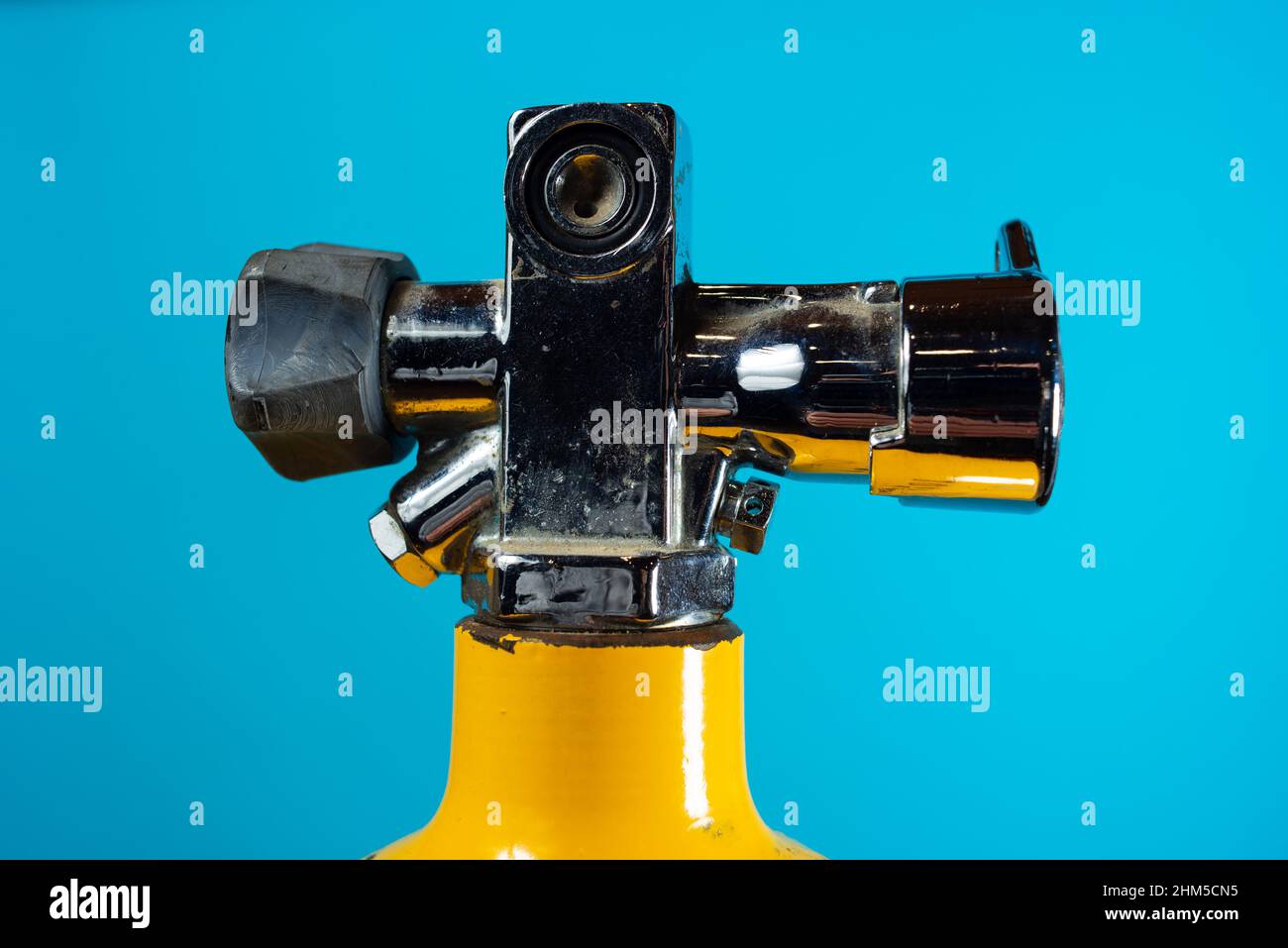 Vintage yellow steel scuba tank and valve with blue background Stock