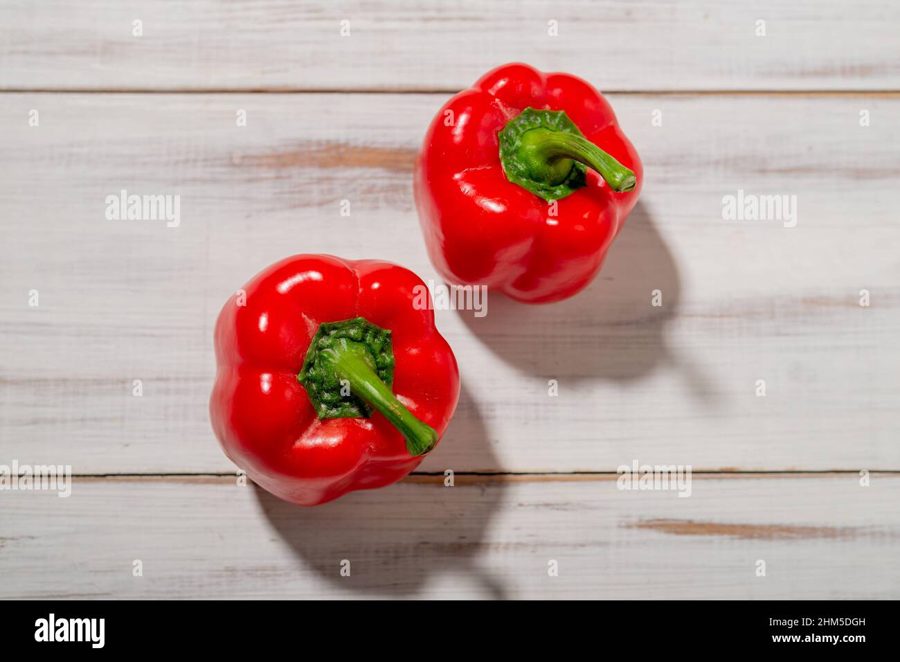 Two red sweet peppers on a wooden background. Light background. Food, vegetarian concept. Stock Photo