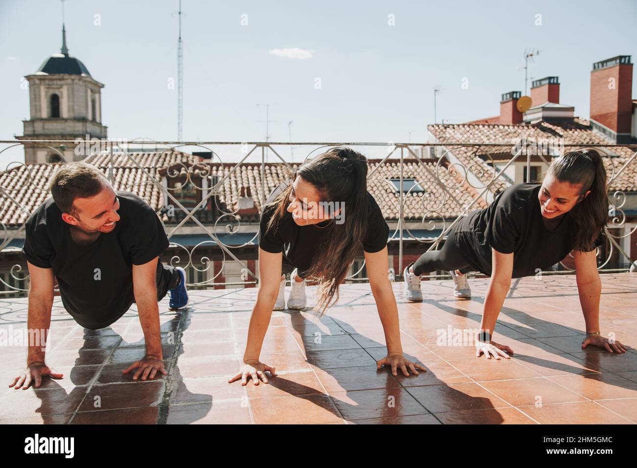 Three people doing push-ups on a rooftop Stock Photo