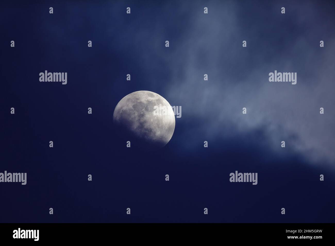 Moon behind dark blue clouds Stock Photo