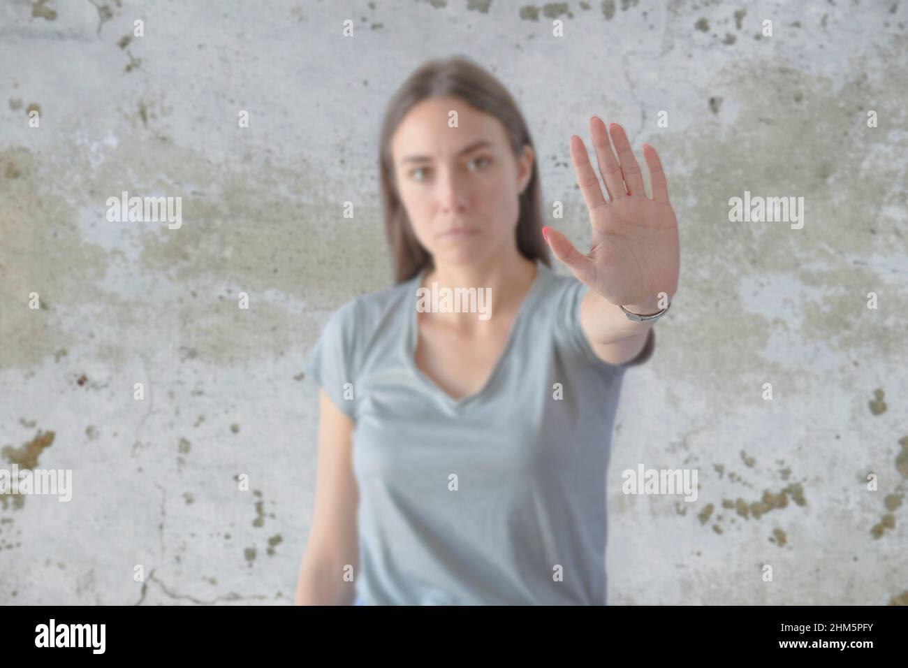 Young woman standing over grunge grey wall doing stop sing with palm of the hand Stock Photo
