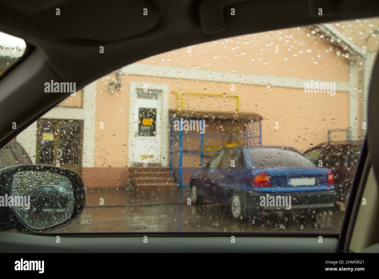 A view from inside a car during a rain shows raindrops on the side ...