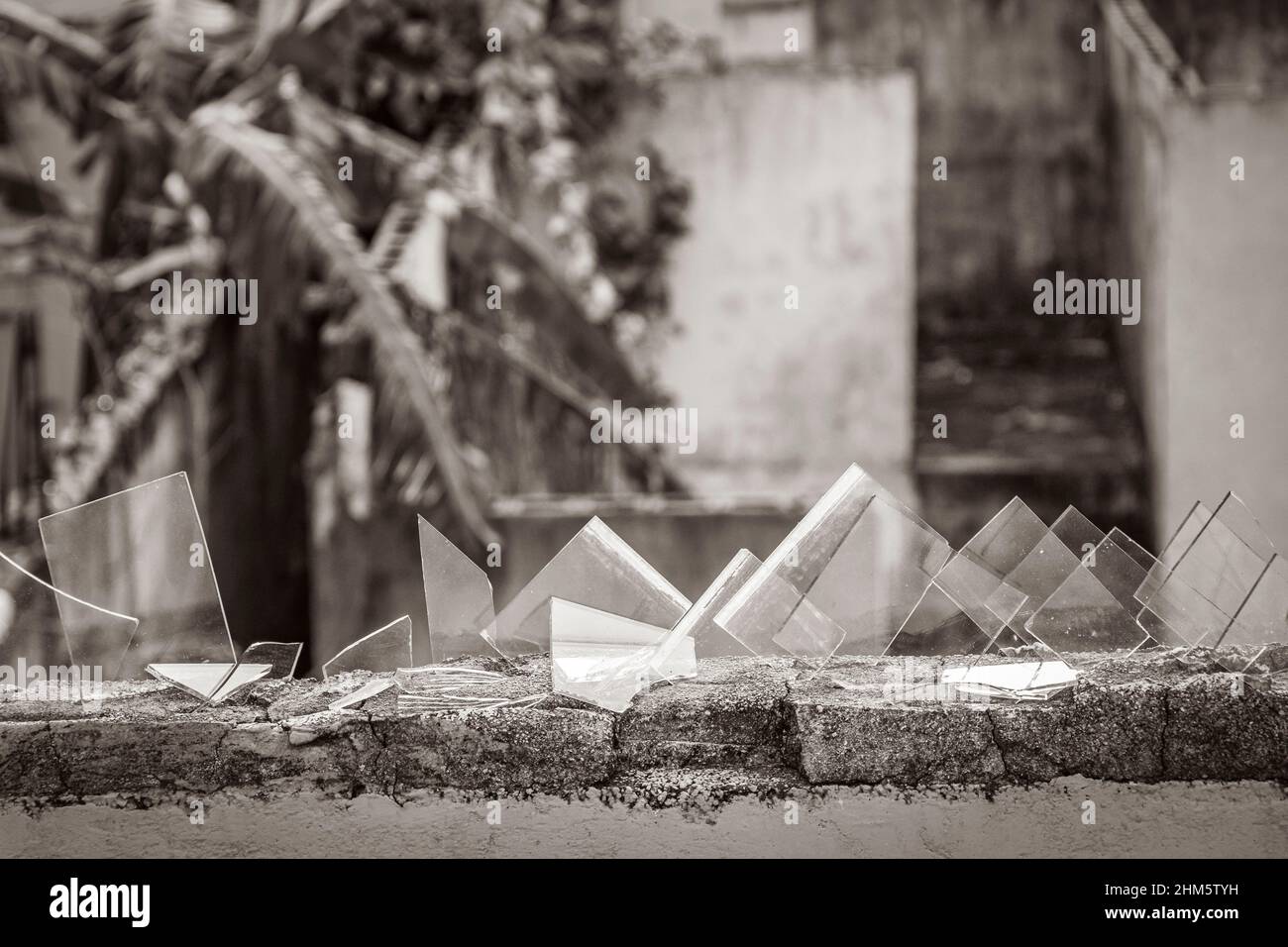 Black and white picture of a dangerous wall with broken glass shards bottles in Luis Donaldo Colosio Playa del Carmen Mexico. Stock Photo