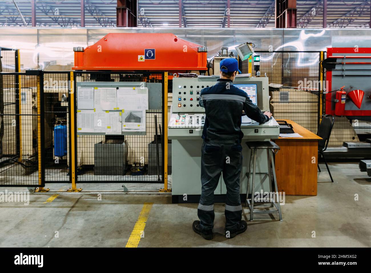 Factory worker operating CNC machine in metalworking workshop. Stock Photo