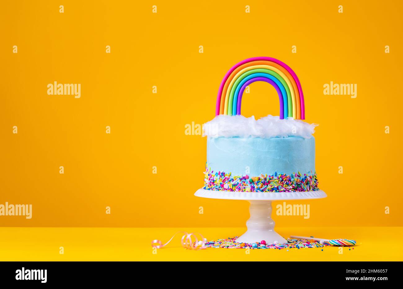 Blue Birthday Cake with Rainbow topper on Yellow Stock Photo