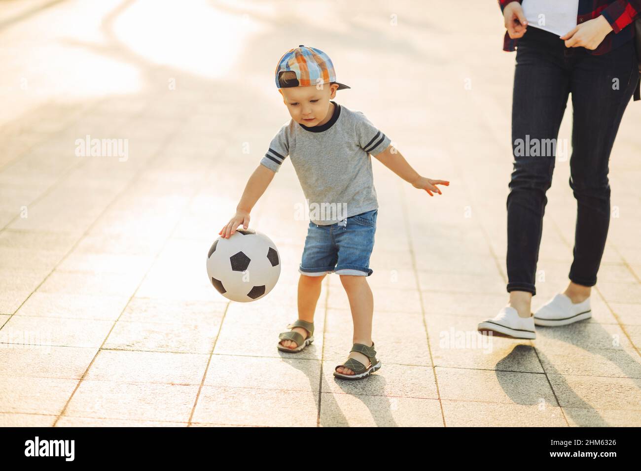 Mom and son play football together outdoors in the park, Little boy