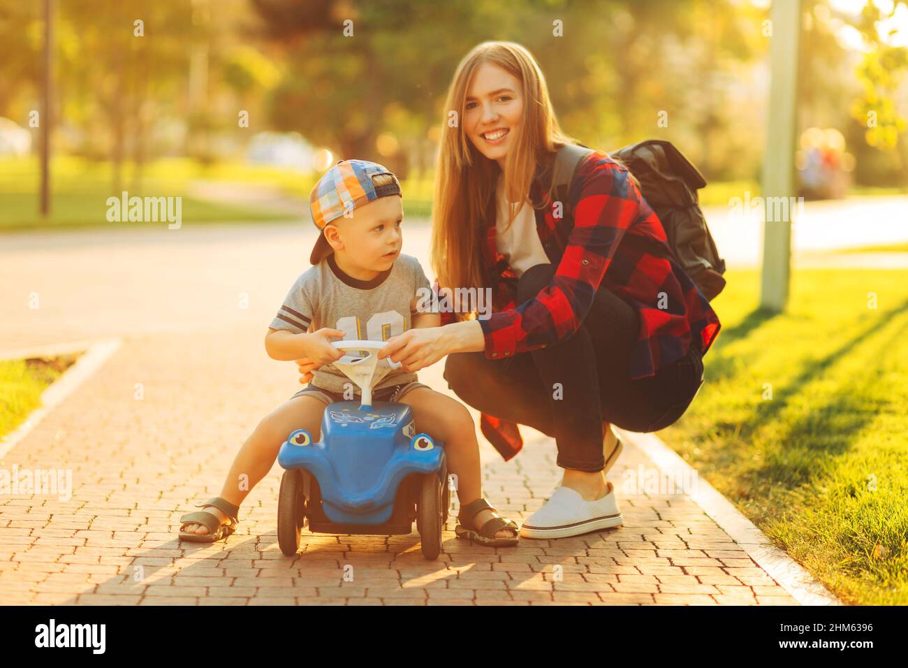 Mom and child are playing with a toy car outdoors in the park. A happy ...