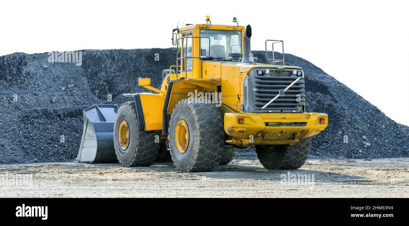 Yellow wheel loader against a pile of gravel isolated on white background Stock Photo