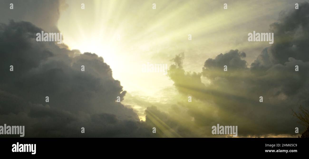 Cloudscape image of dark stormy clouds in blue sky with sun beam. The ...