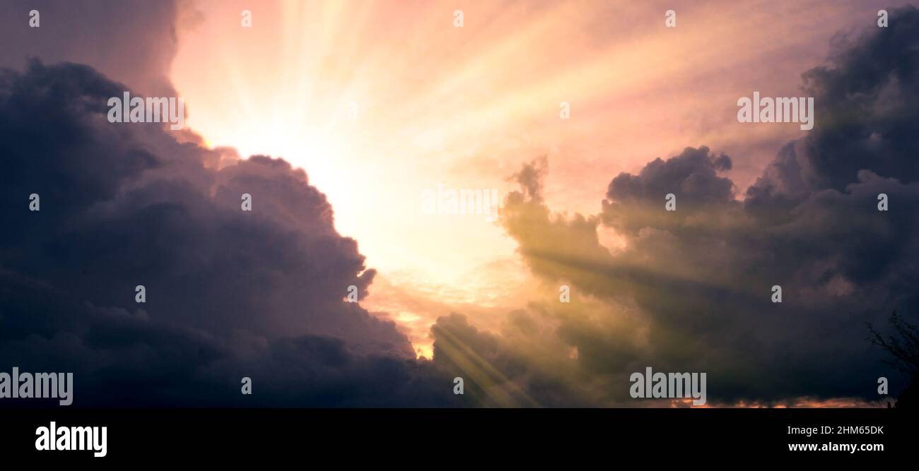 Cloudscape image of dark stormy clouds in blue sky with sun beam. The ...