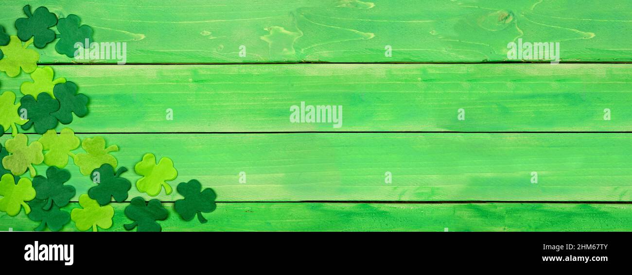 St Patricks Day banner with corner border of shamrocks. Above view over a green wood background. Copy space. Stock Photo