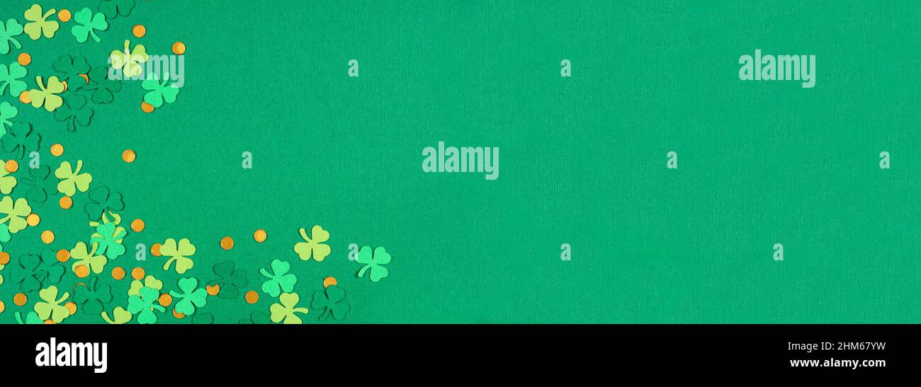 St Patricks Day green background with shamrock and gold coin confetti corner border. Overhead view banner with copy space. Stock Photo
