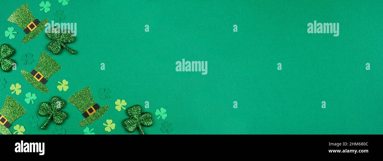 St Patricks Day shamrock and leprechaun hat corner border. Overhead view over a green paper banner background with copy space. Stock Photo