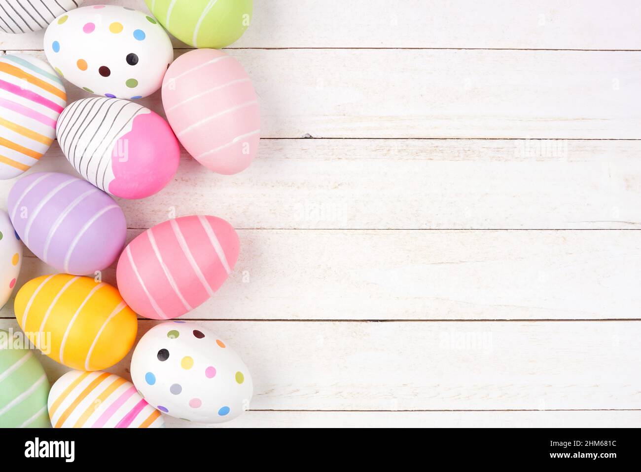 Colorful Easter Egg side border. Above view against a white wood background. Copy space. Stock Photo