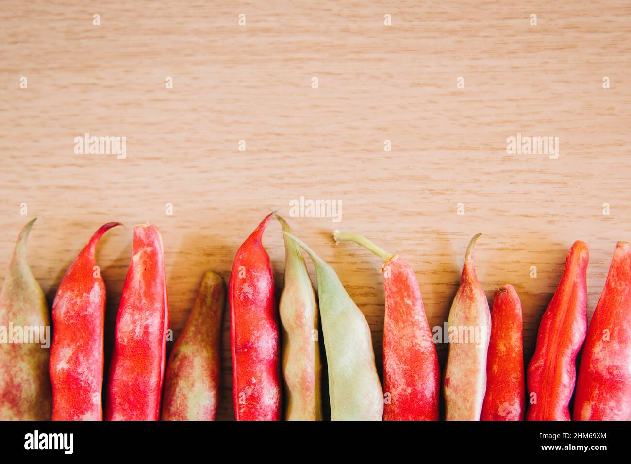 Row of red and green shell beans over a wooden table. Healthy food and organic concept. Stock Photo