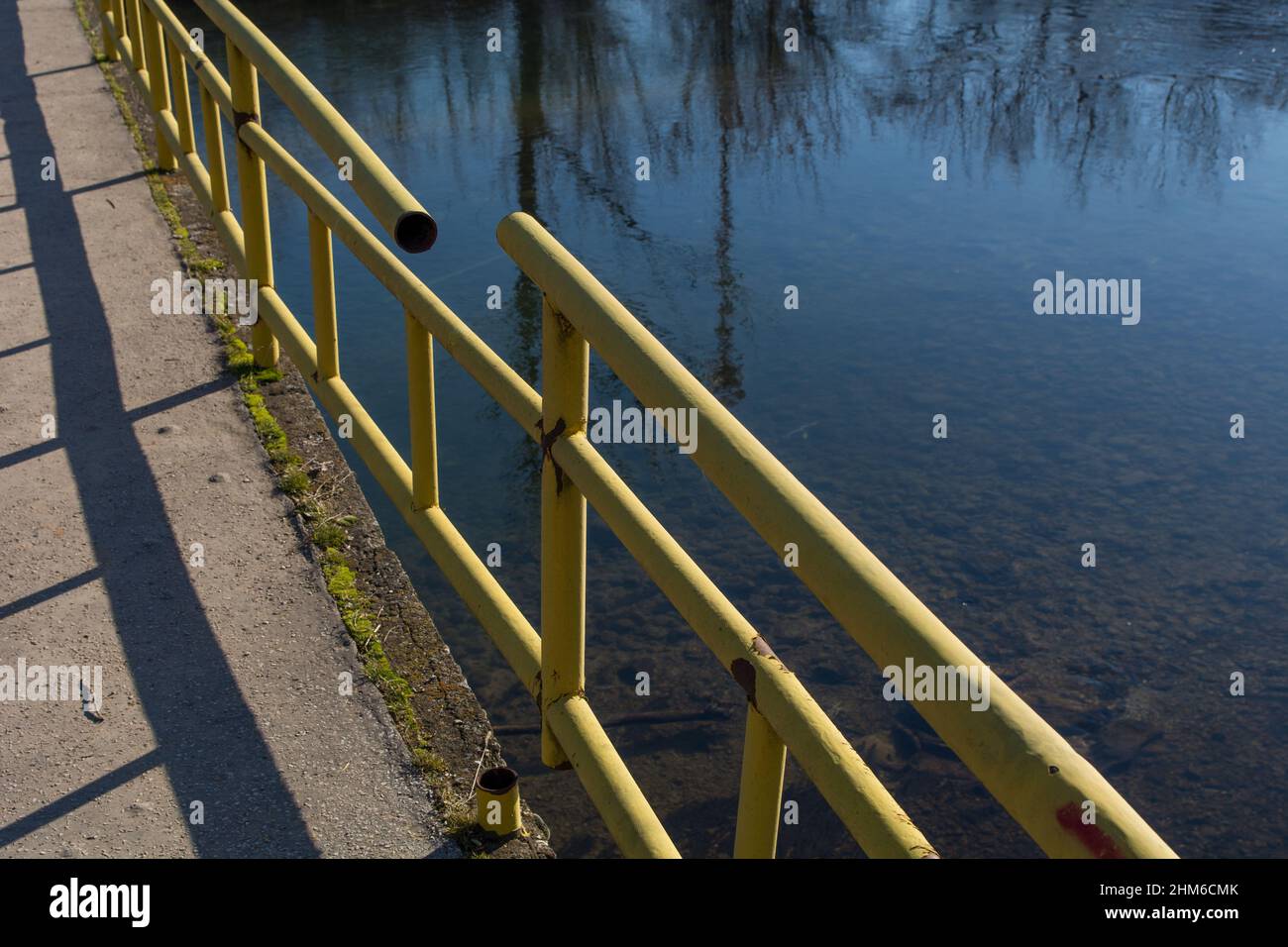 The broken fence on the bridge over the river. Dangerous and damaged bridge for pedestrians and cars Stock Photo