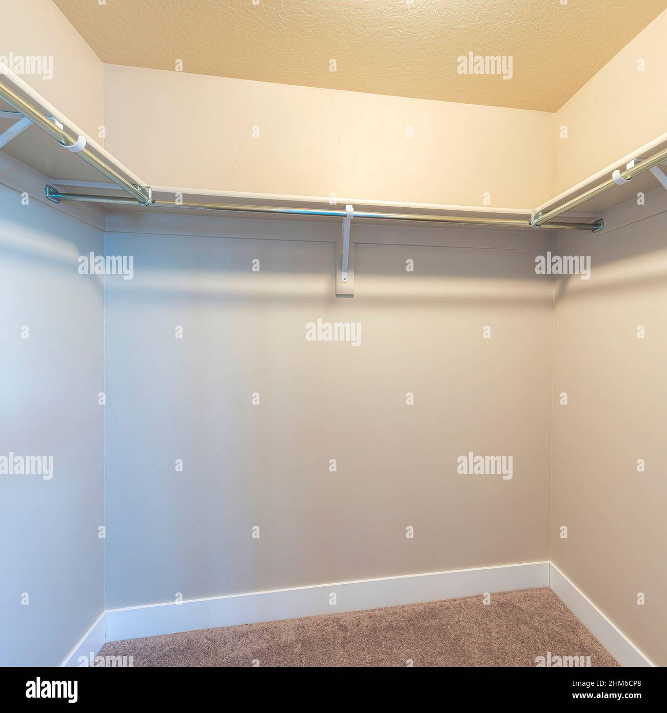 Square Small walkin closet with shelves and metal rods below Stock