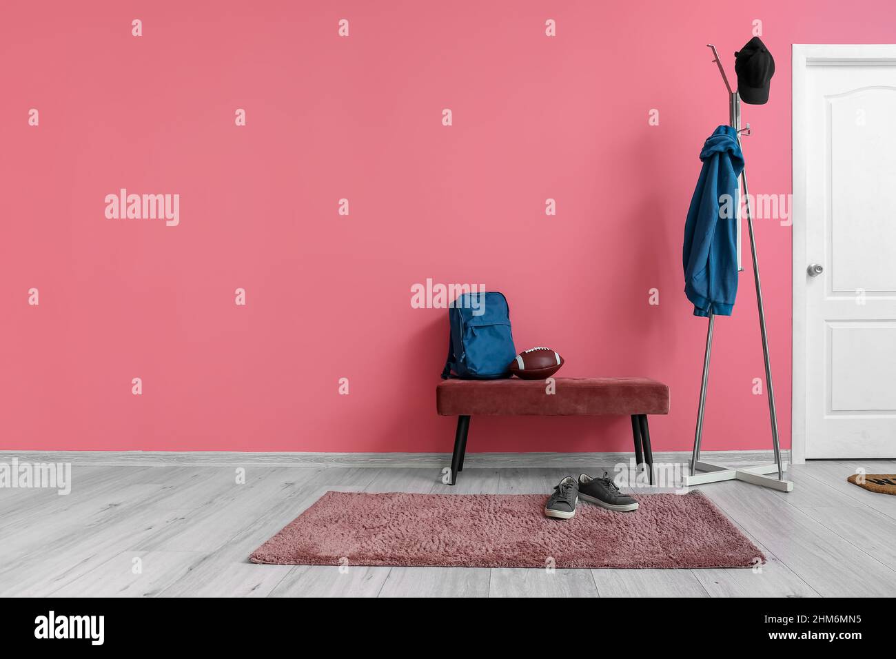 Interior of stylish hall with ottoman, rugby ball and rack Stock Photo