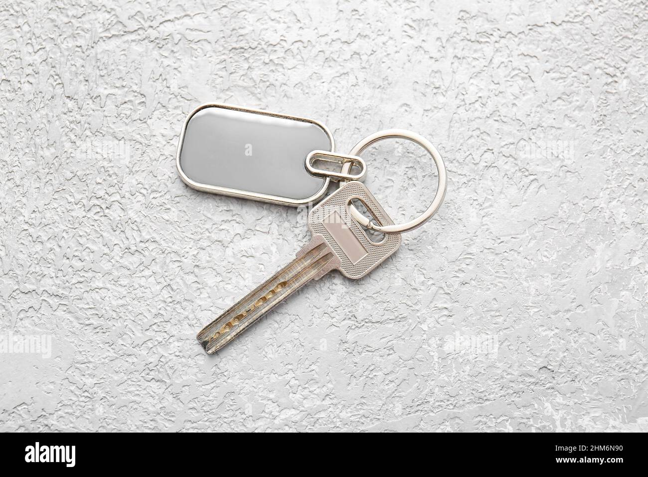 Key with stylish metallic keychain on light background Stock Photo