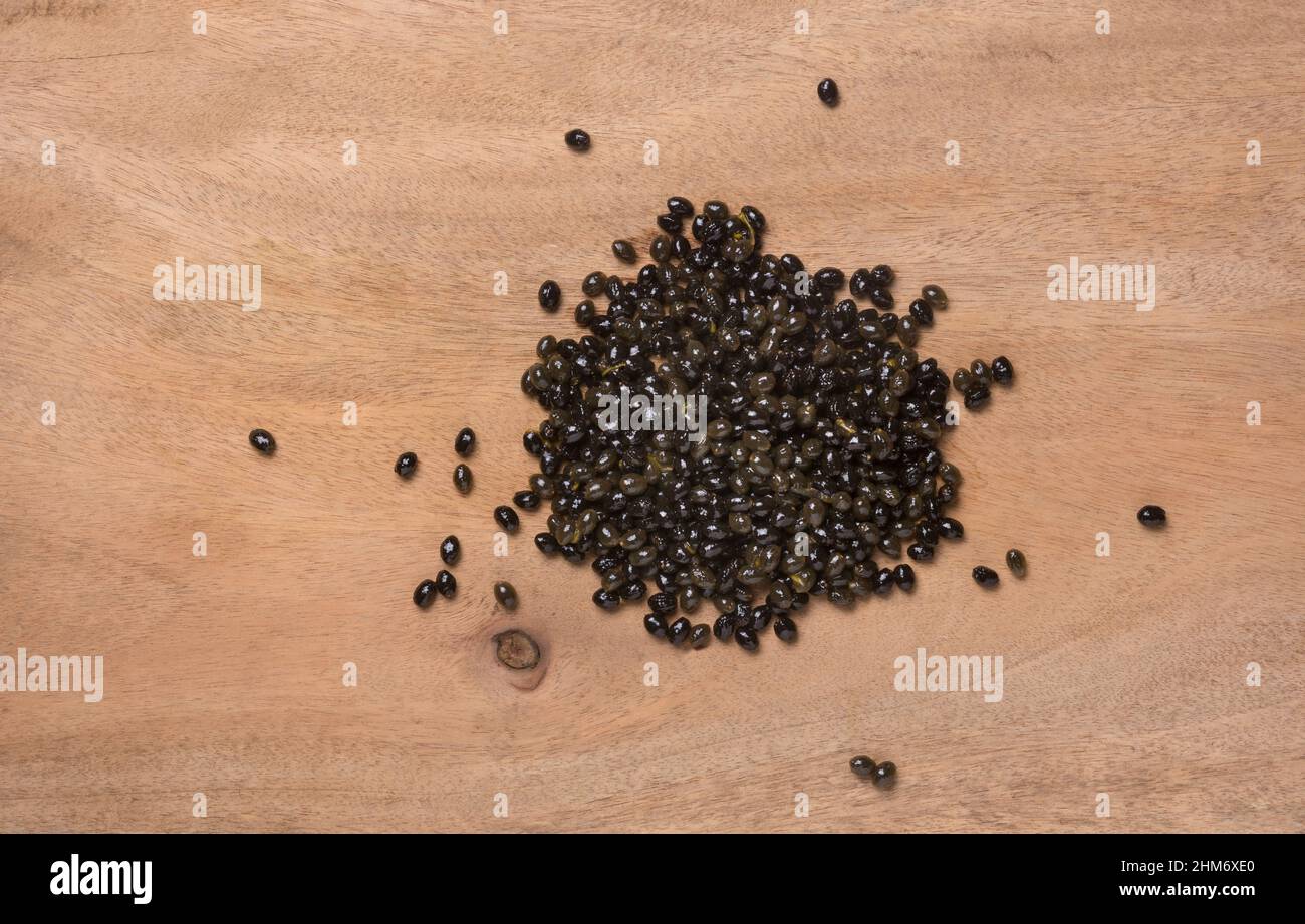 fresh raw papaya seeds from ripe papaya on a wooden table top, beneficial and highly nutritious edible black, shiny, wet seeds, heart healthy food Stock Photo