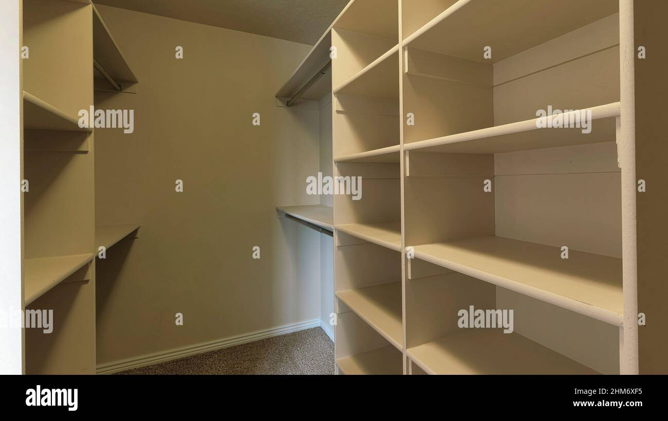 Panorama Empty walk-in closet with framed shelves and metal rods Stock ...