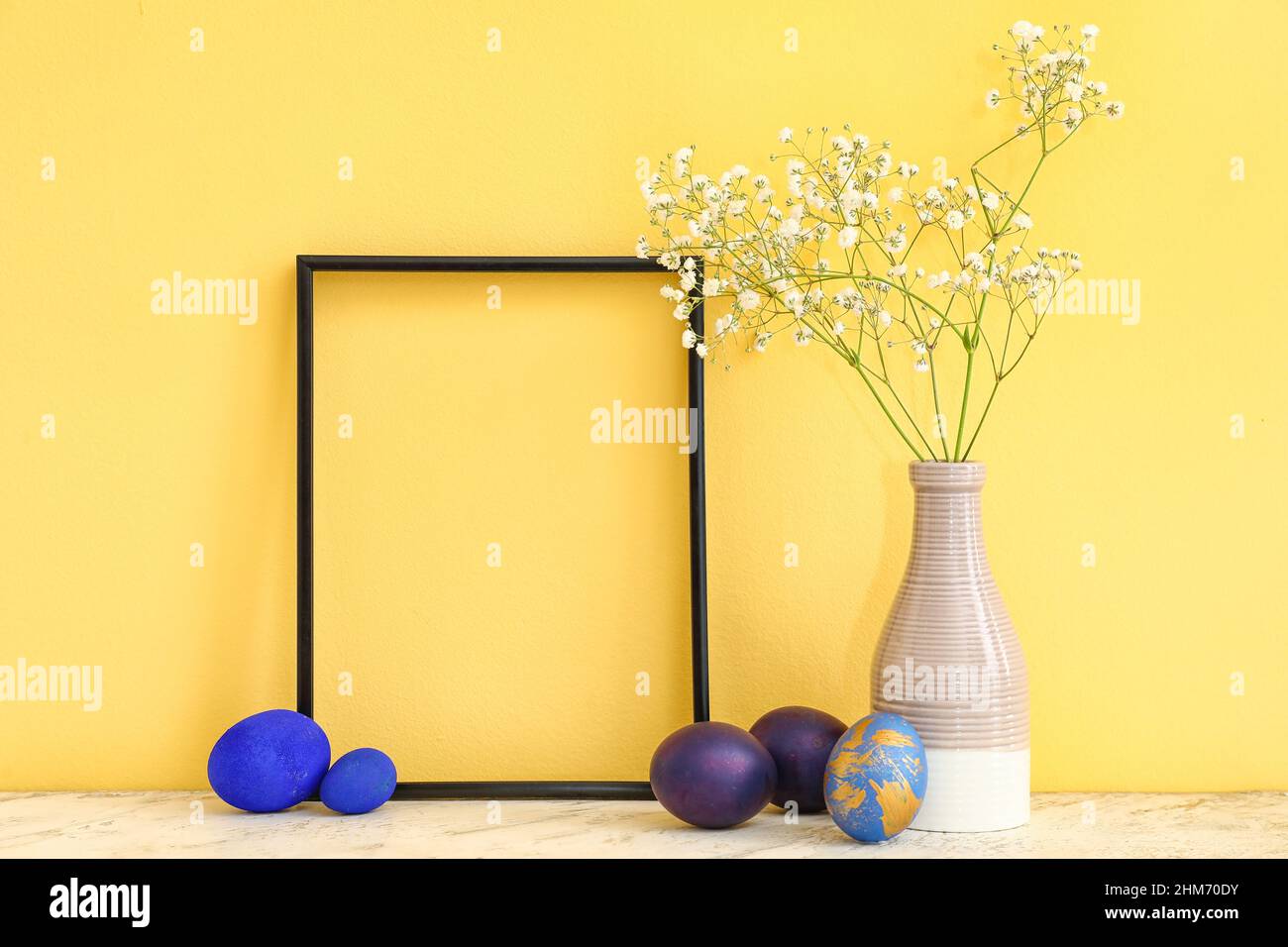 Empty picture frame, vase with gypsophila flowers and Easter eggs on ...