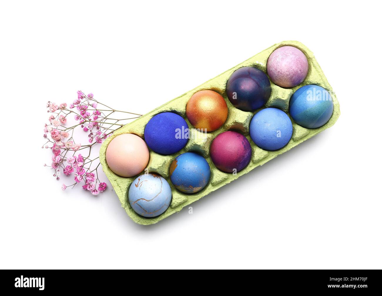Holder with beautiful Easter eggs and gypsophila flowers on white ...