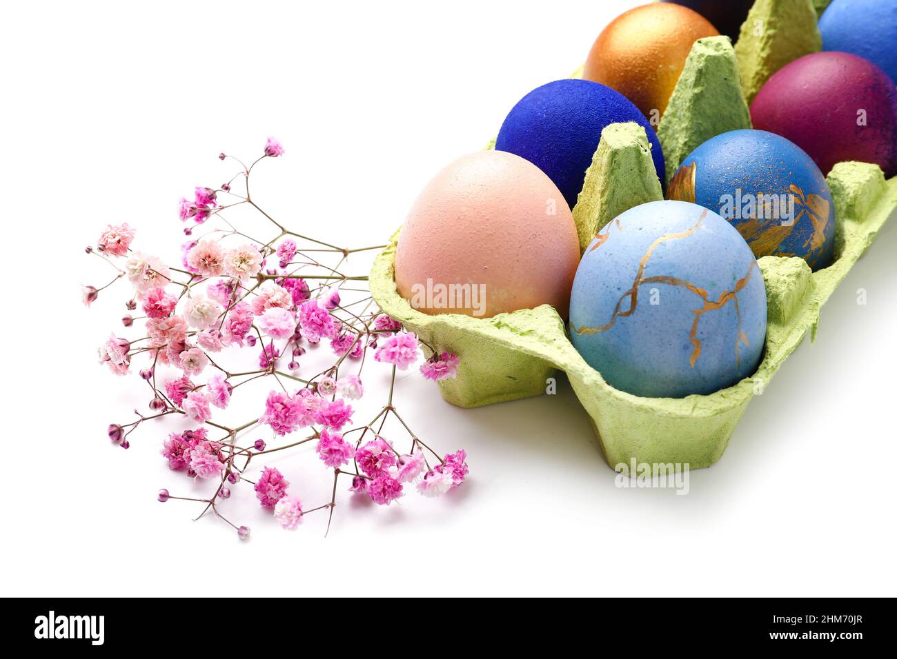 Holder with beautiful Easter eggs and gypsophila flowers on white ...