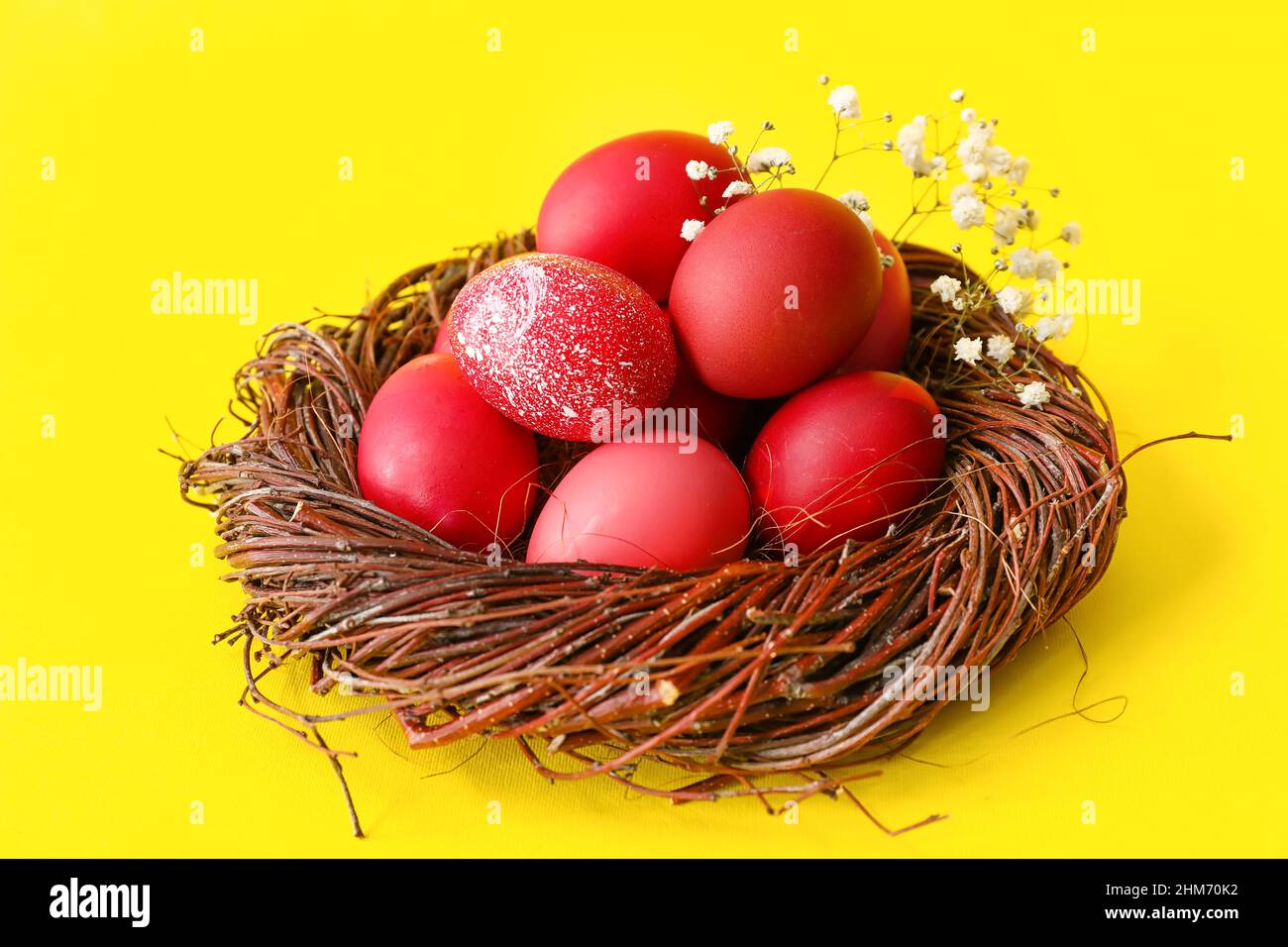 Nest with beautiful Easter eggs and flowers on yellow background Stock ...