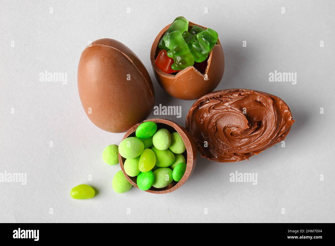 Delicious Easter eggs with candies and chocolate paste on light background Stock Photo