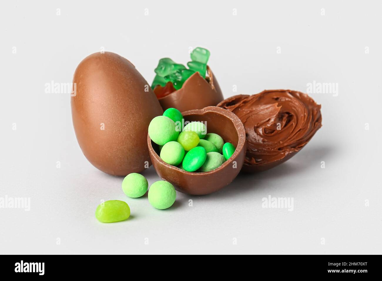 Delicious Easter eggs with candies and chocolate paste on light background Stock Photo