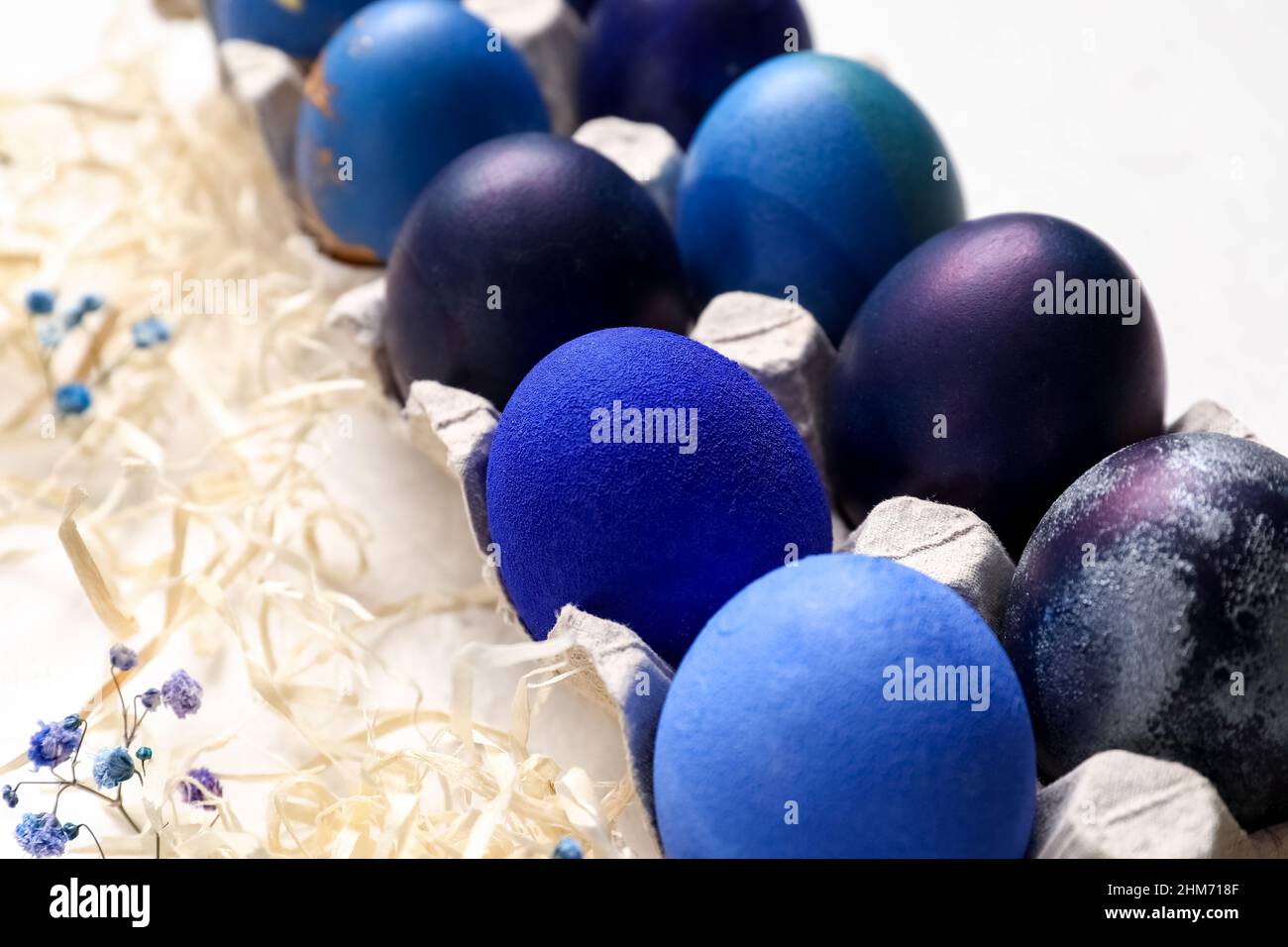 Holder with painted Easter eggs and gypsophila flowers on light ...