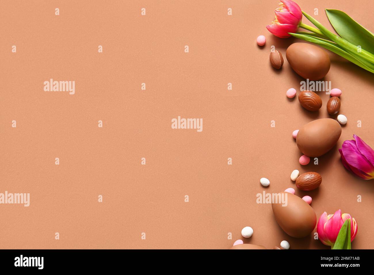 Composition with chocolate Easter eggs and flowers on color background Stock Photo