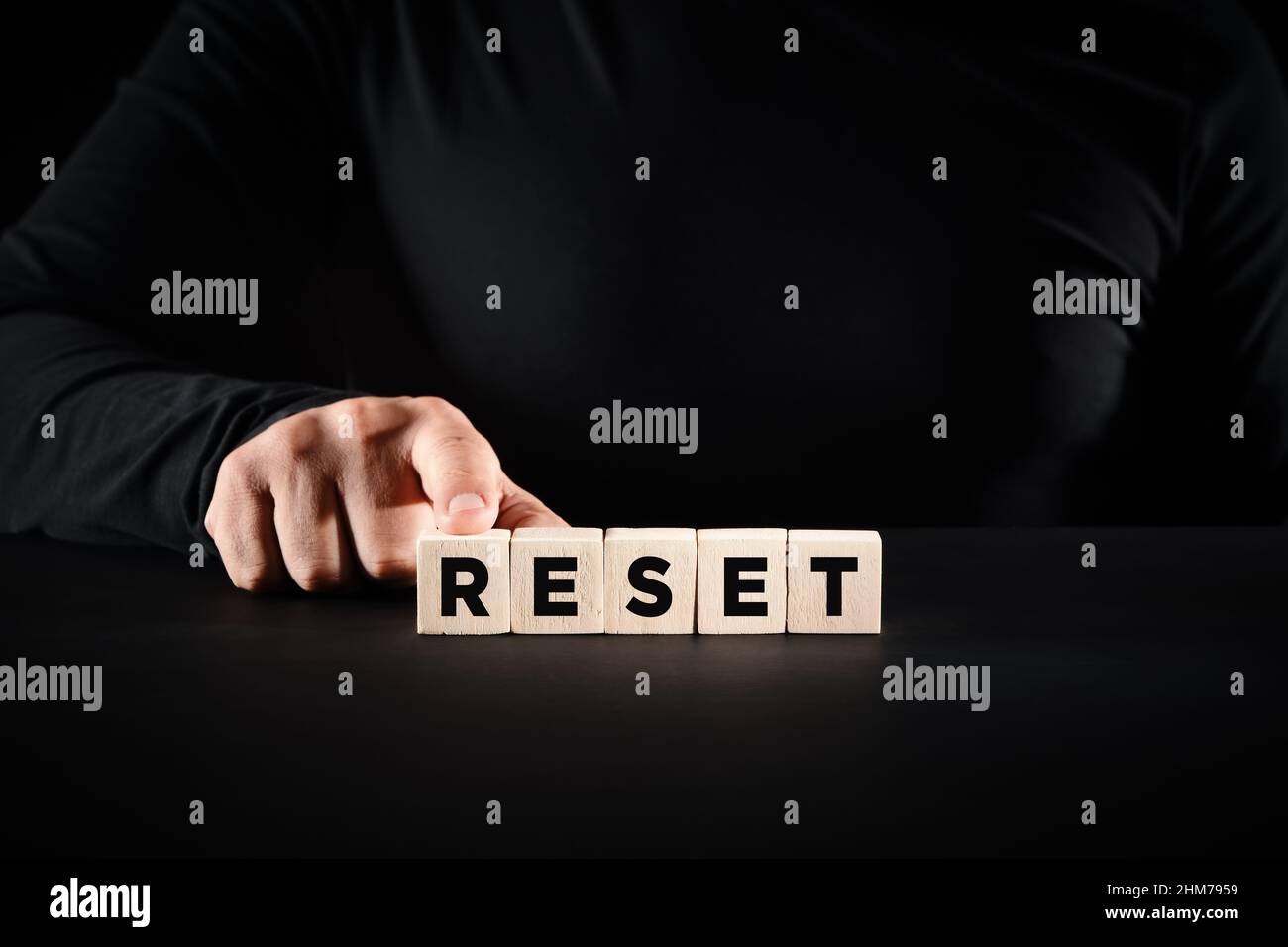 Male hand pressing the wooden blocks with the word reset. To make a new beginning and resetting computer, life, business or career concept. Stock Photo