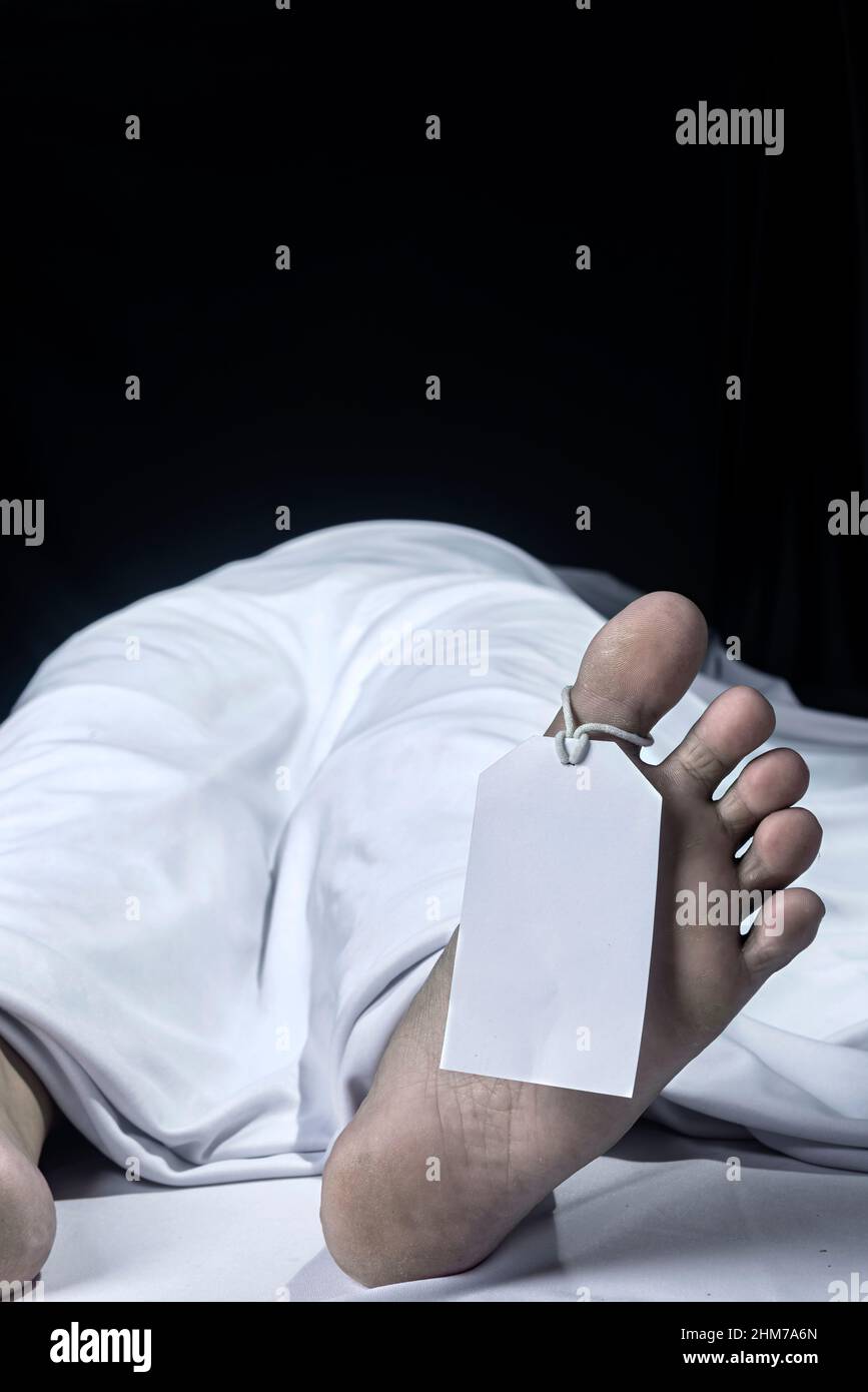Human corpse covered with a sheet and name tag on toe in the