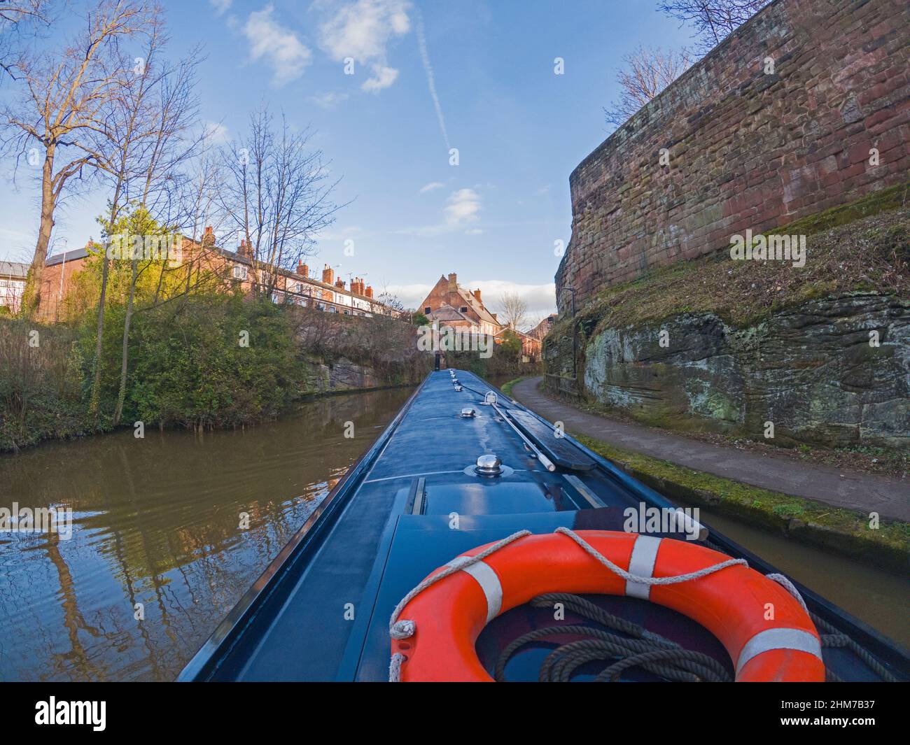 View from narrowboat traveling through English urban scenery on British canal with old city walls Stock Photo