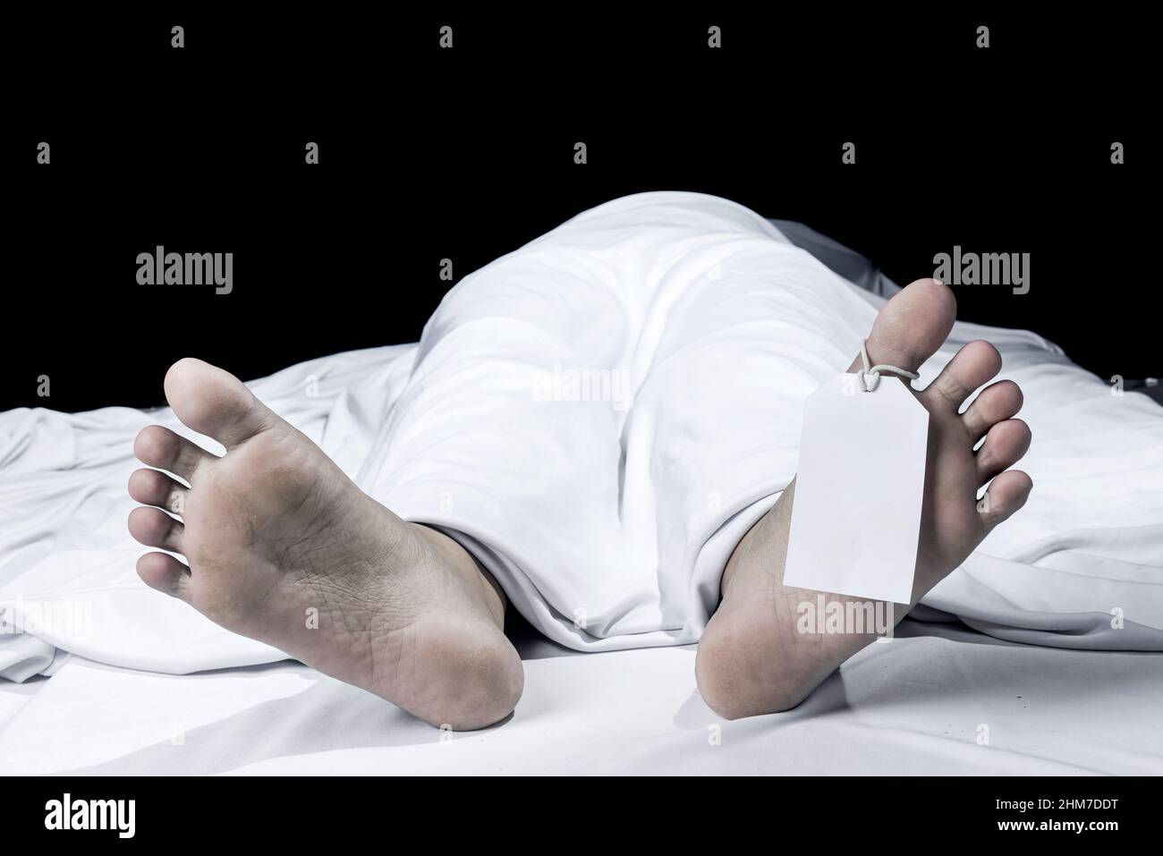 Human corpse covered with a sheet and name tag on toe in the