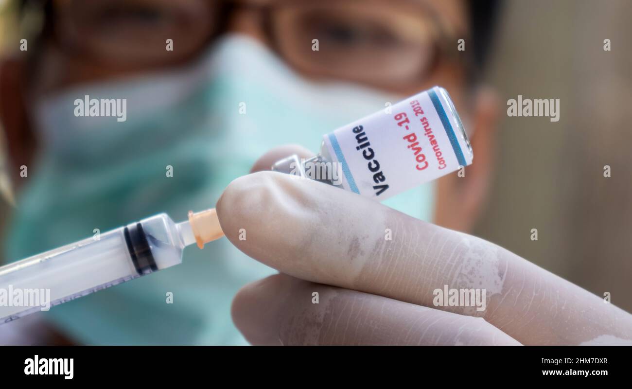 Concept fight against virus covid-19 corona virus, doctor or scientist in laboratory holding a syringe with liquid vaccines for children or older adul Stock Photo