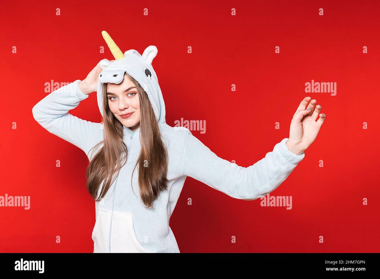 Girl in unicorn pajamas on a red background. Overnight stay. Time to