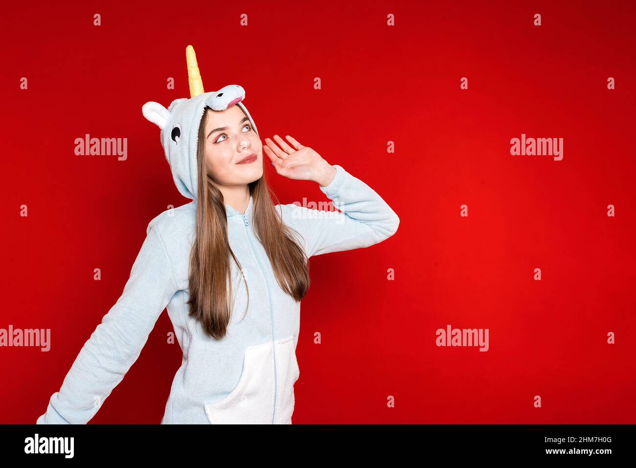 Girl in unicorn pajamas on a red background. Overnight stay. Time to