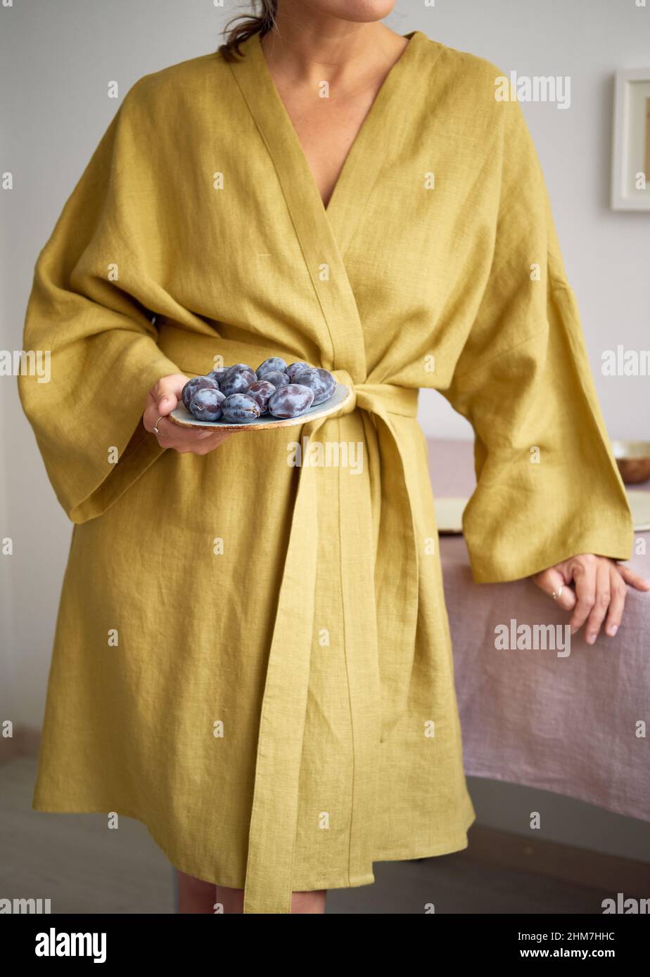 Young girl in a dressing gown lays the table. Natural fabrics and