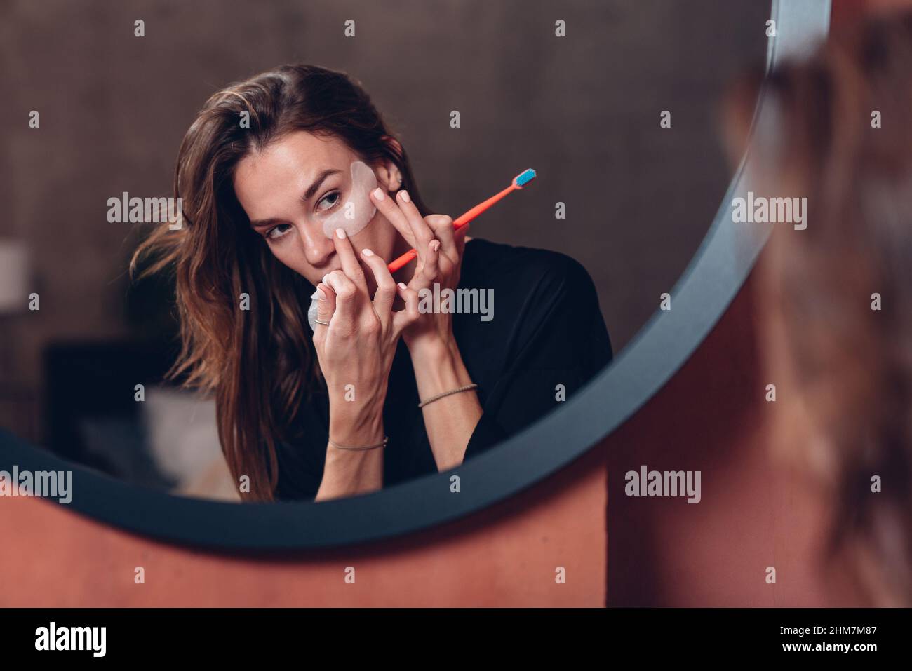 Woman brushes her teeth, puts patches under her eyes before going to
