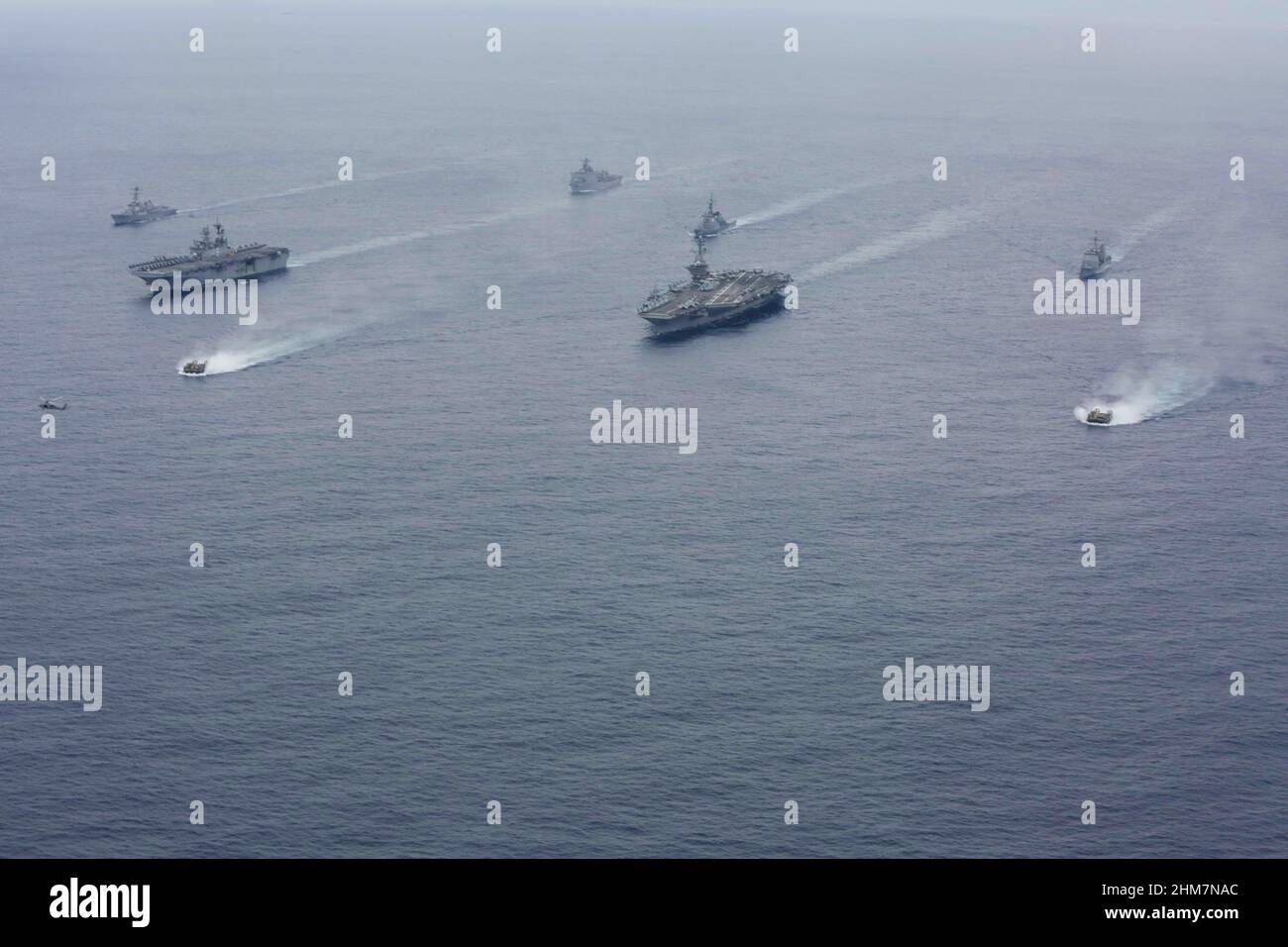 PHILIPPINE SEA (Feb. 7, 2022) Ships of the America and Essex Amphibious Ready Groups, and Abraham Lincoln Carrier Strike Group, sail in formation with the Japan Maritime Self-Defense Force during exercise Noble Fusion. Front row: Landing craft, air cushion from the USS Essex (LHD 2). Second row, left to right: USS America (LHA 6), USS Abraham Lincoln (CVN 72) Third row, left to right: USS Dewey (DDG 105), JS Kongō (DDG 173), USS Mobile Bay (CG 53). Back row: USS Ashland (LSD 48). Ships of the America and Essex Amphibious Ready Groups and the Abraham Lincoln Carrier Strike Group, alongside the Stock Photo