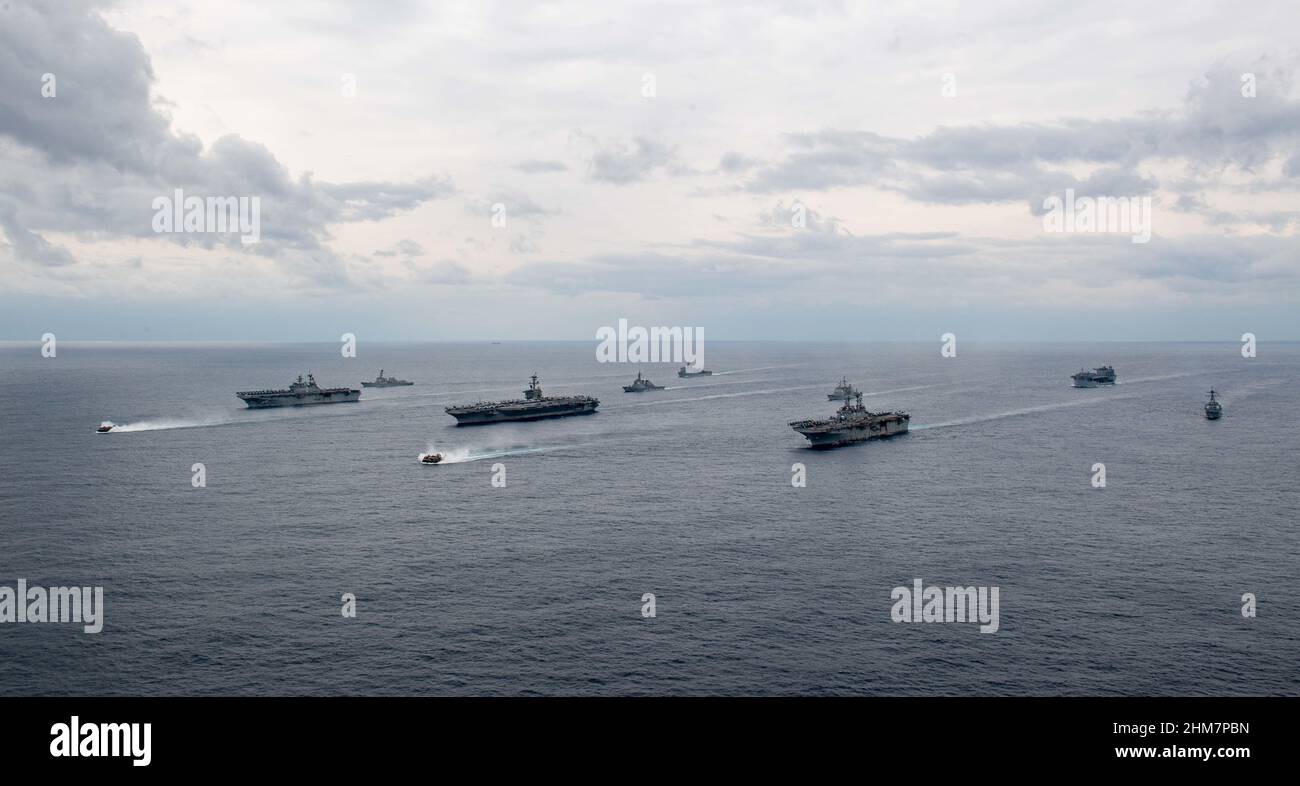 PHILIPPINE SEA (Feb. 7, 2022) Ships of the America and Essex Amphibious Ready Groups, and Carrier Strike Group (CSG) 3, sail in formation with the Japan Maritime Self-Defense Force during exercise Noble Fusion. Left to right: Landing craft, air cushion from Assault Craft Unit (ACU) 5, USS America (LHA 6), USS Dewey (DDG 105), landing craft, air cushion from ACU 5, USS Abraham Lincoln (CVN 72), JS Kongō (DDG 173), USS Ashland (LSD 48), USS Essex (LHD 2), USS Mobile Bay (CG 53), USS Miguel Keith (ESB 5), USS Spruance (DDG 111). Noble Fusion demonstrates that Navy and Marine Corps forward-deploye Stock Photo