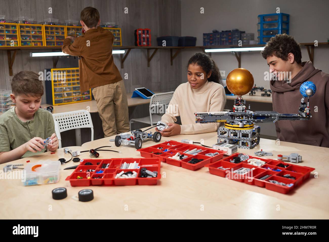 Diverse group of teenage children building robots in engineering class at modern school, copy space Stock Photo