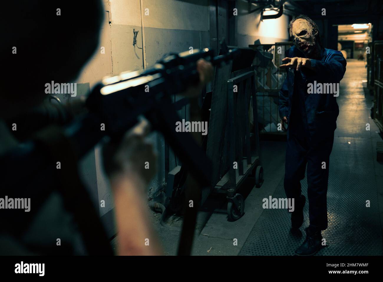 Close up of fighter pointing gun at zombie in dark hallway, post apocalyptic setting, copy space Stock Photo