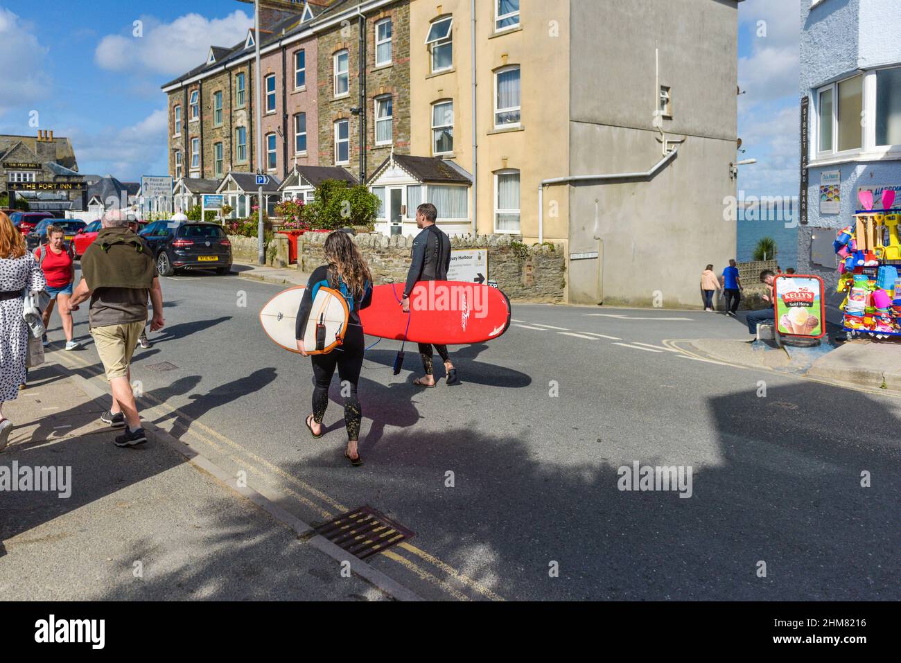 Surfers carrying their surfboards and walking along a road in Newquay Town centre on the North